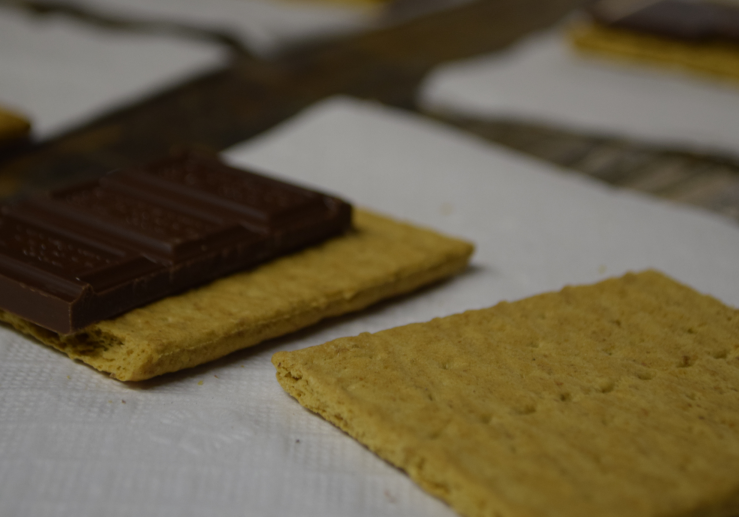 A chocolate bar placed on a rectangular biscuit on a white napkin.